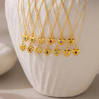 North Star Birthstone Heart Necklaces featuring vibrant gemstones are elegantly displayed on a white textured vase, showcasing personalized jewelry in heart-shaped designs.