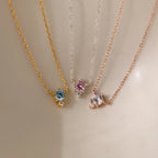The Dainty Birthstone Drop Necklace features three delicate chains with round blue, pink, and clear gemstone pendants—ideal for wearing as a dainty necklace or unique birthstone accessory on any occasion.