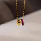 The Duo Circle Birthstone Necklace features a gold chain with a plain gold pendant and a circle charm adorned with red gemstones—ideal as a birthstone necklace or personalized jewelry gift.