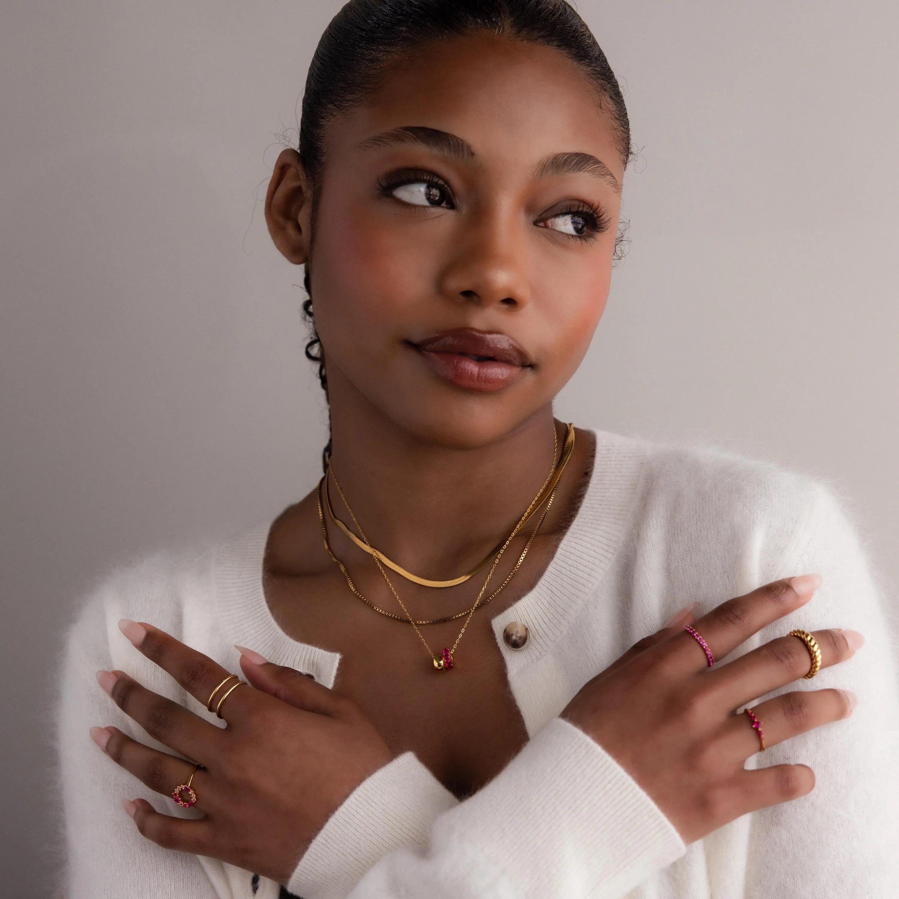 Woman wearing the Duo Circle Birthstone Necklace layered with a circle charm, styled with a white sweater and posing with arms crossed.