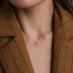 The Pave Initial Tag Necklace features two sparkling pendant charms, ideal as a personalized initial necklace and stylishly worn over a brown pinstripe blazer.