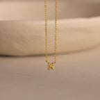 Close-up of the gold Custom Bubble Initial Necklace with the letter K, displayed on a neutral surface.