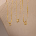 Three dainty gold Custom Bubble Initial Necklaces with the letters S, K, and G hanging side by side against a neutral background.