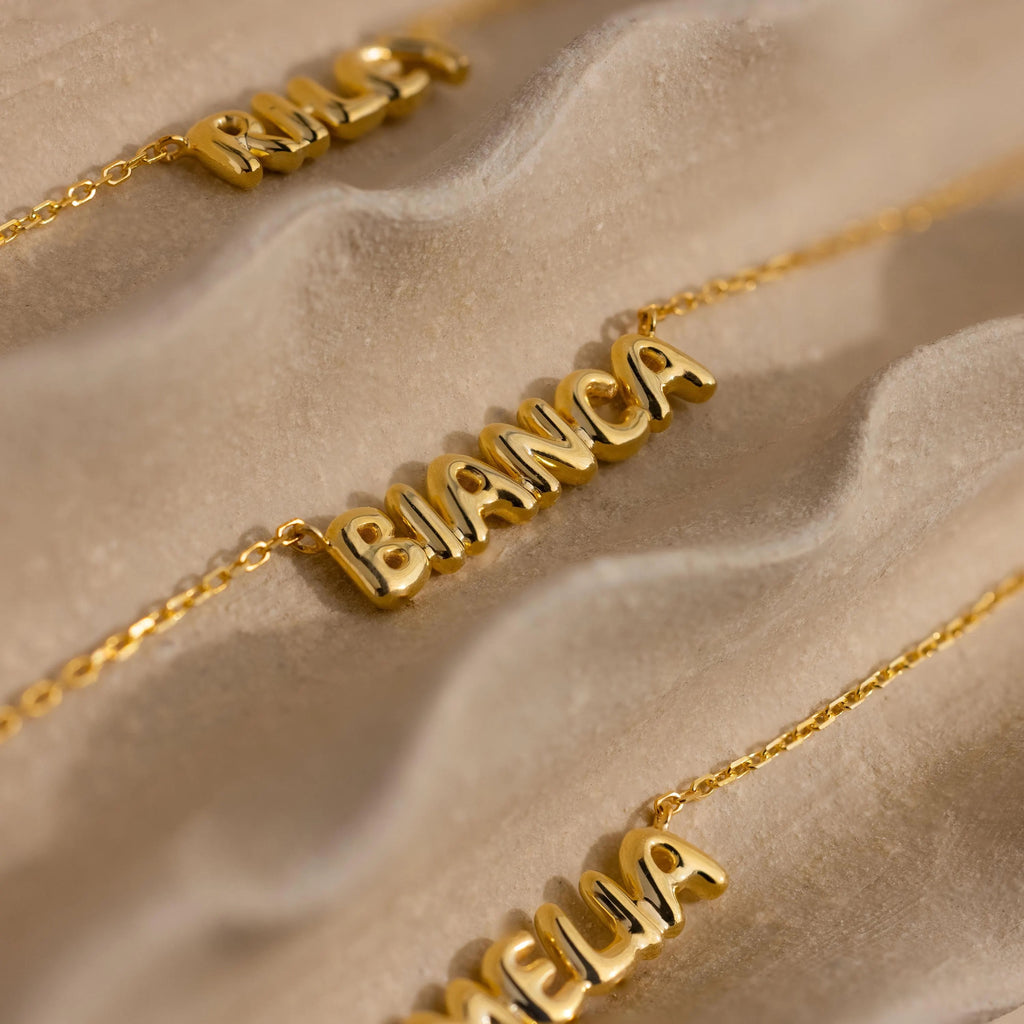 Close up of Bianca gold bubble name necklace, with Riley and Amelia name necklace on the sides