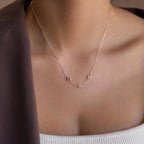 The Multiple Bubble Letter Necklace features silver bubble letters M and H, styled with a white top and brown jacket—a unique boho accessory that complements any outfit.