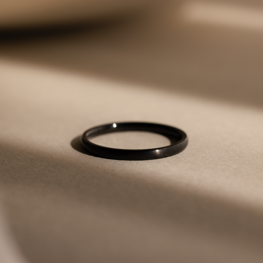 The Classic Men's Black Rings Set, ideal for any men's jewelry collection, is displayed on a smooth beige surface with soft, dramatic lighting and shadows.