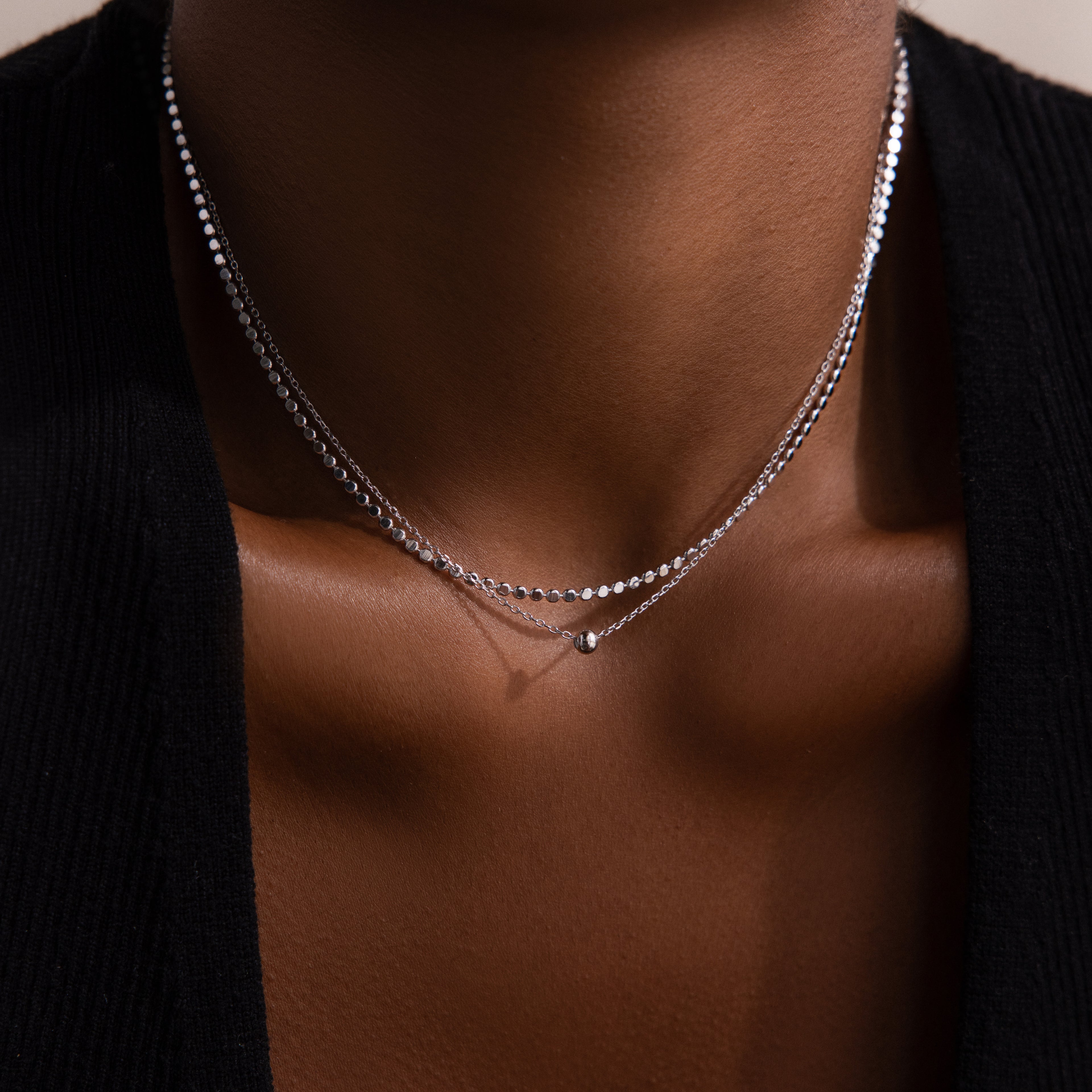 Silver beaded duo necklace on a woman wearing a black garment