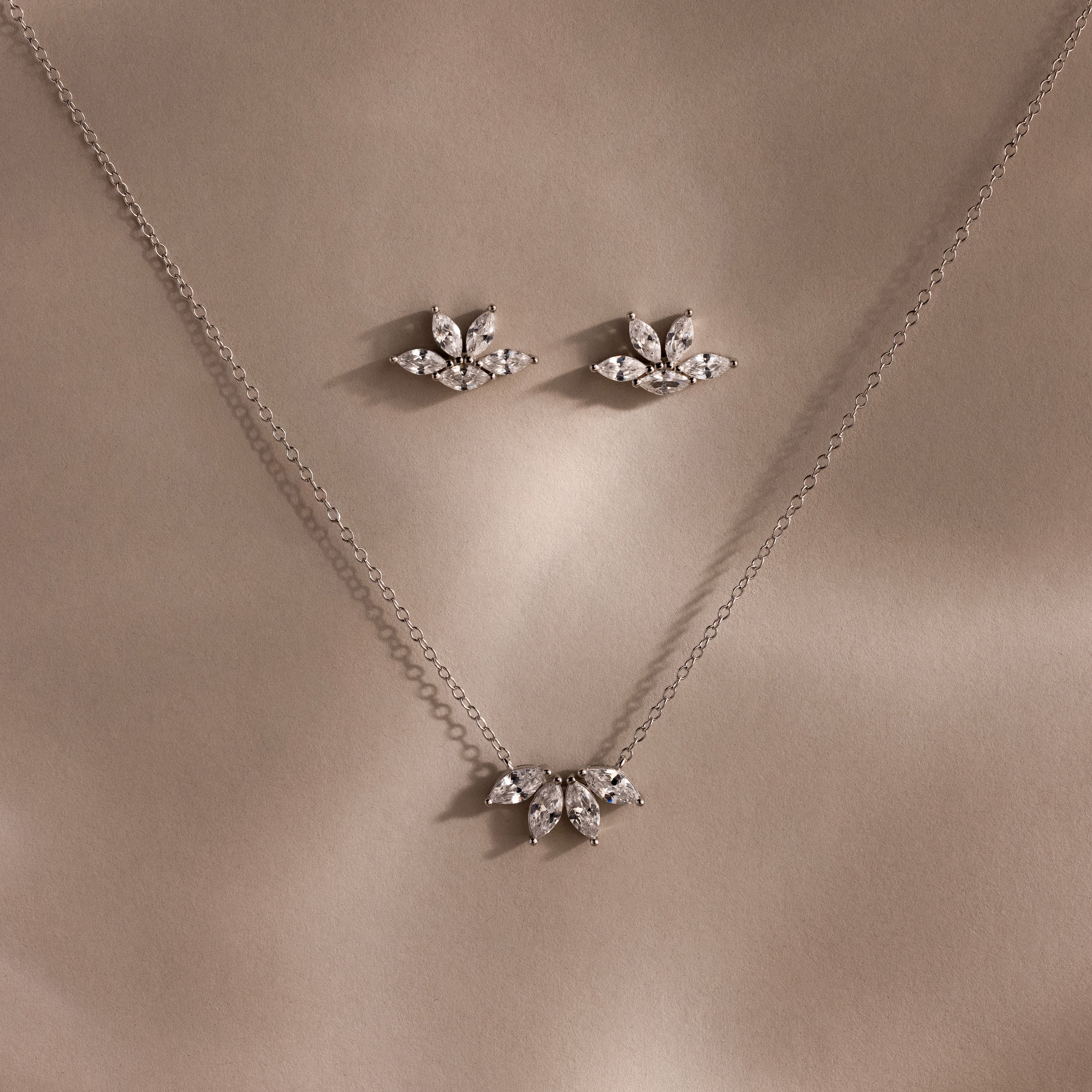 Marquise Diamond Jewelry Set in Sterling Silver: Features a necklace and earrings with leaf-inspired, diamond-like designs—perfect for bridal wear, elegantly presented on a neutral beige background.