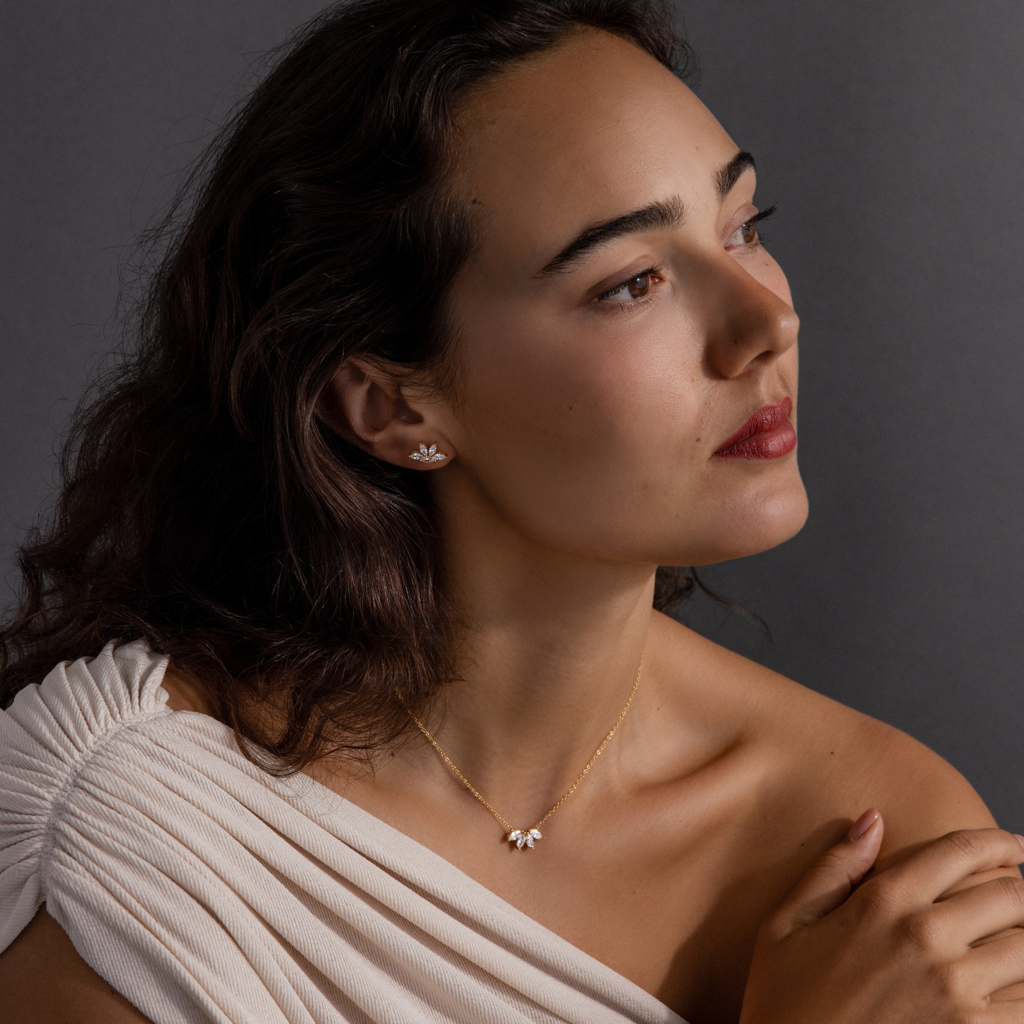 Woman in a white off-shoulder top wearing a lotus-shaped diamond necklace and matching earrings from the Marquise Diamond Jewelry Set in 18K Gold, looking to the side—an ideal wedding gift.