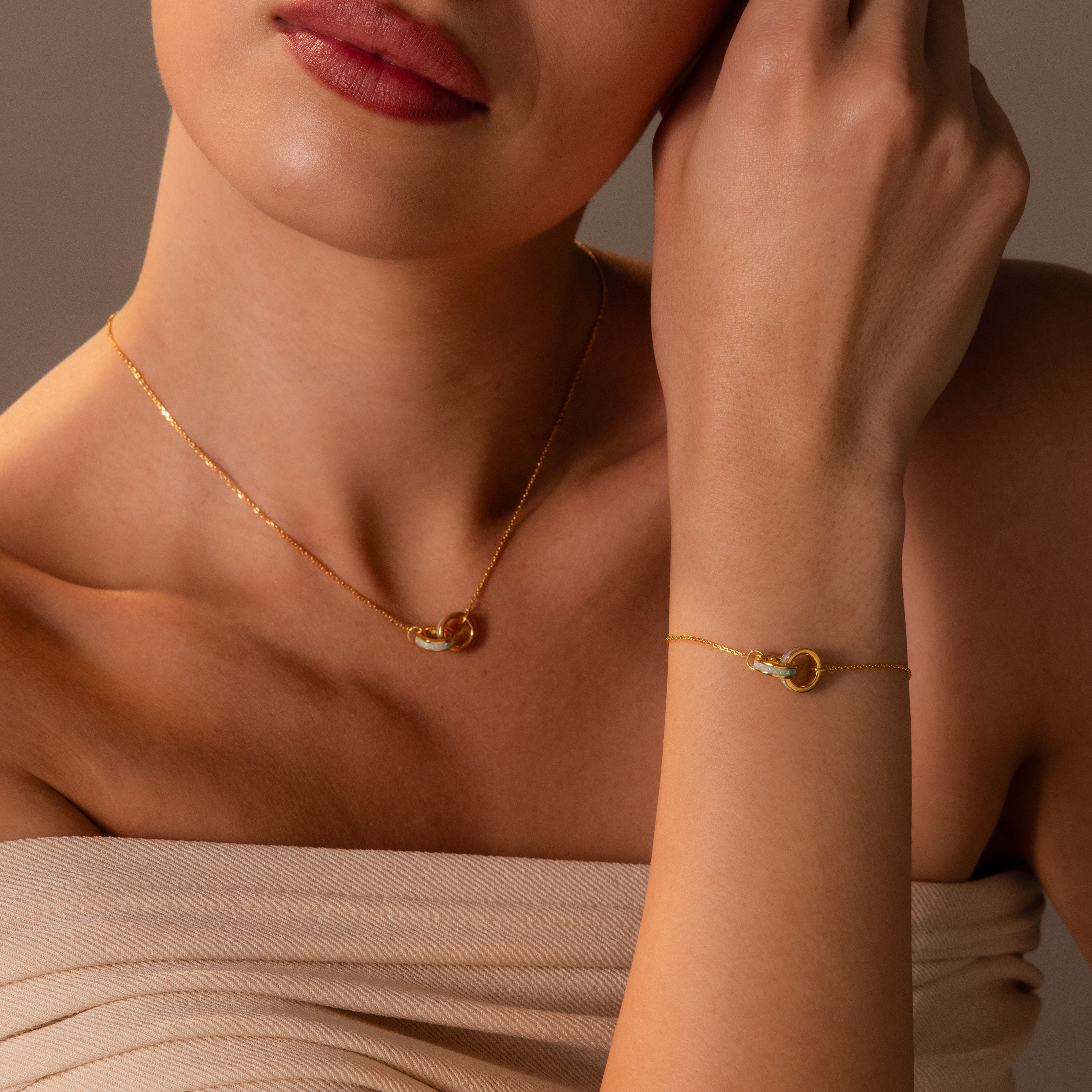 A woman wearing the Interlocking Opal Inlay Necklace and Bracelet Set, featuring elegant gold rings with circle pendants.