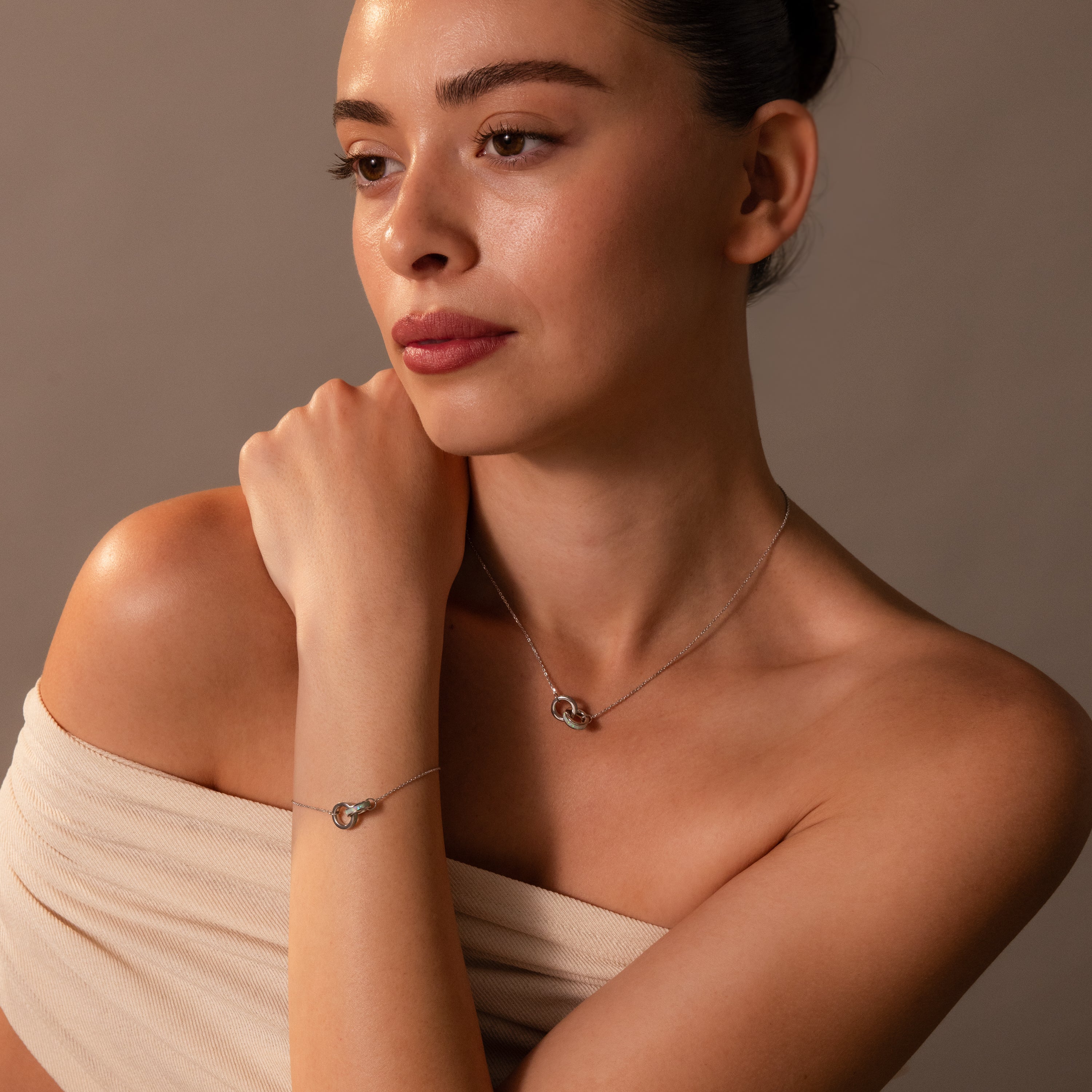 Woman with bare shoulders wearing the Interlocking Opal Inlay Necklace and Bracelet Set, posing against a neutral background.