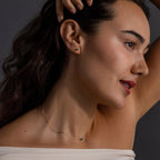 Woman with wavy brown hair poses in profile, wearing the Jade Bar Jewelry Set in 18K Gold, featuring a jade necklace and matching jade stud earrings.