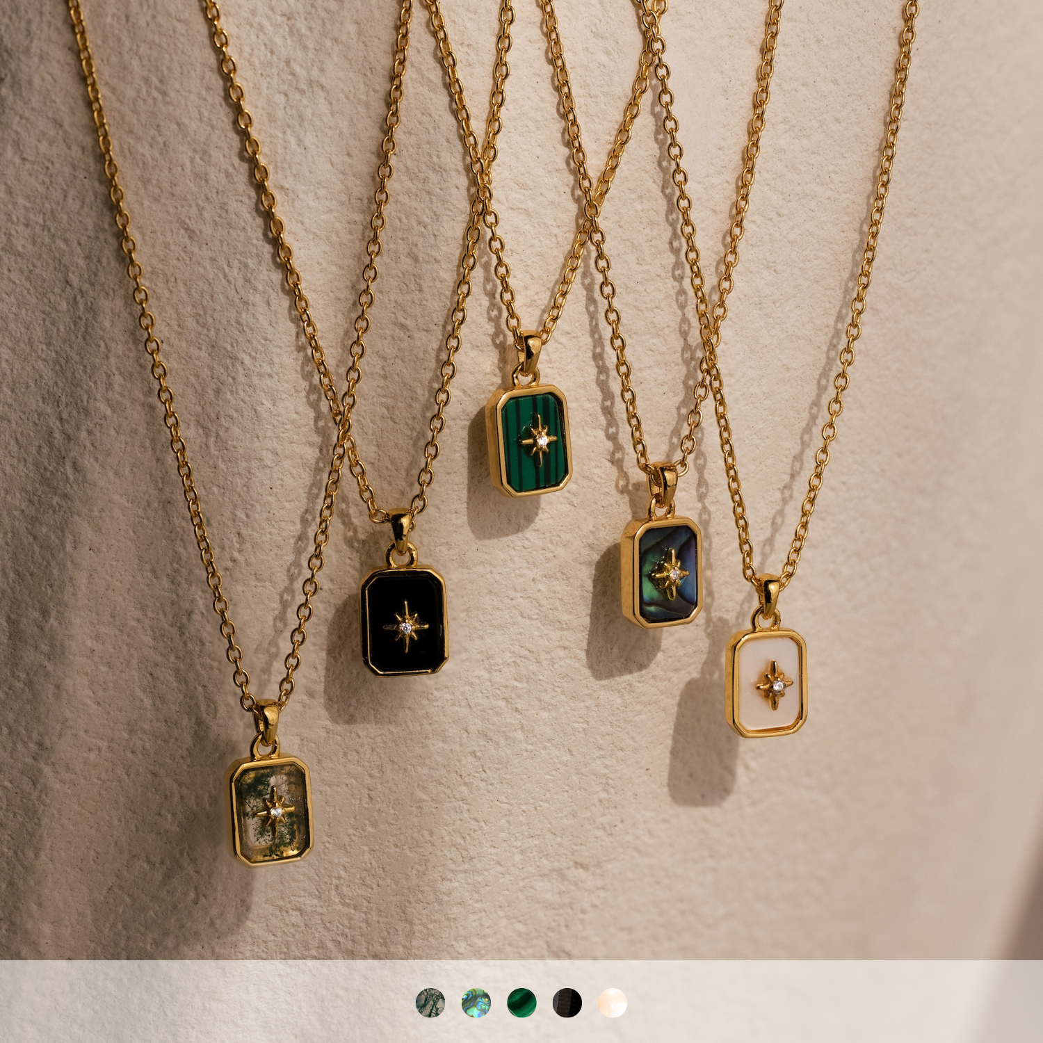 Five North Star Gemstone Necklaces in 18K Gold, each featuring a rectangular crystal pendant, are displayed against a soft beige background.