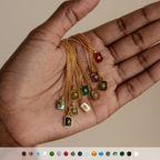A hand holds six North Star Necklaces, featuring crystal pendants and colorful gemstone accents, displayed above a row of gemstone icons.