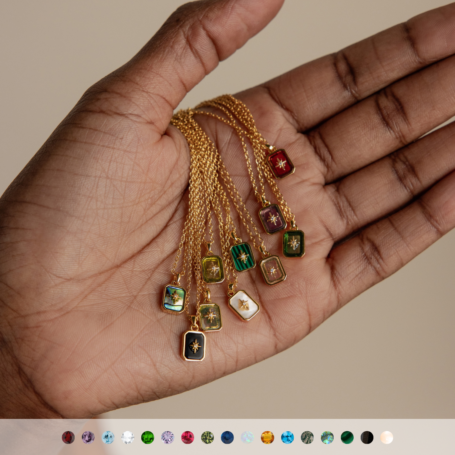 A hand holds six North Star Necklaces, featuring crystal pendants and colorful gemstone accents, displayed above a row of gemstone icons.