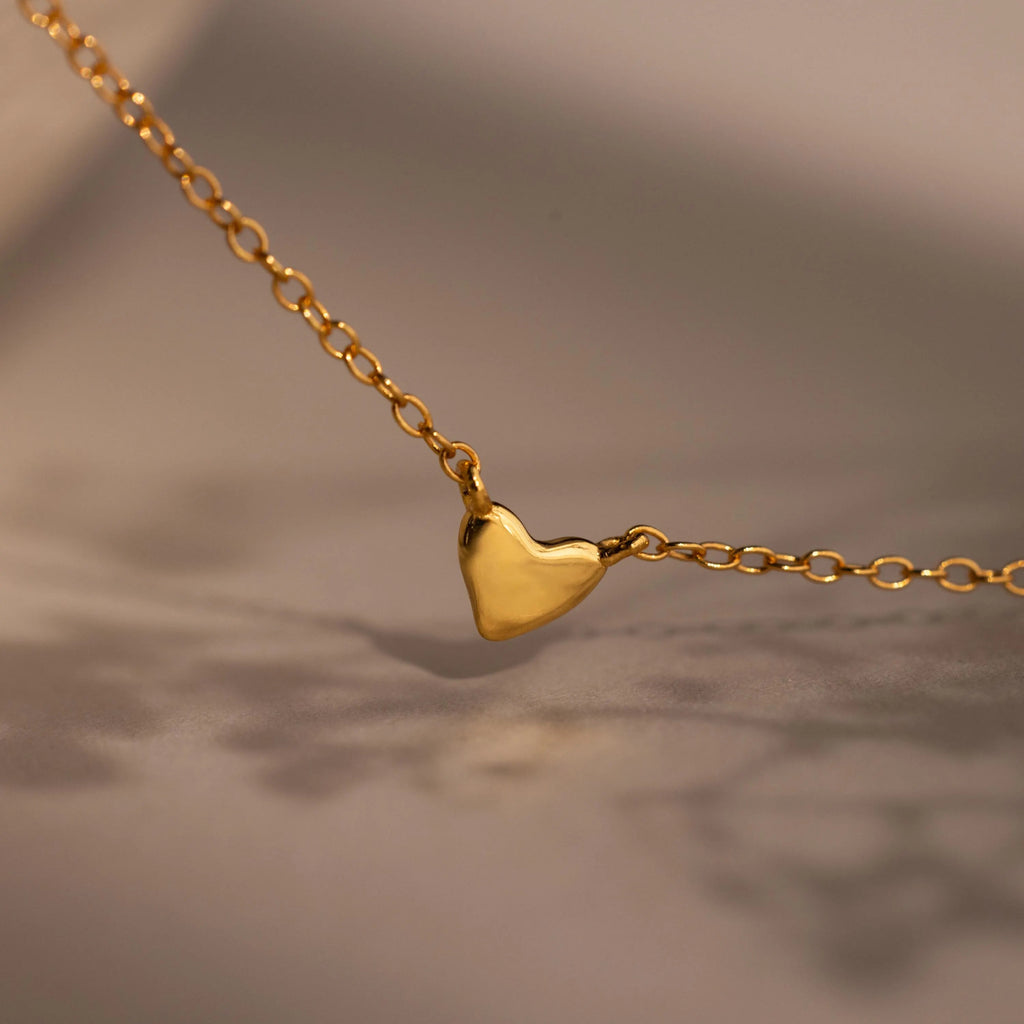 Heart Station Necklace featuring a delicate gold cable chain and a small, simple heart pendant, beautifully displayed against a soft, blurred background.