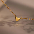 Heart Station Necklace featuring a delicate gold cable chain and a small, simple heart pendant, beautifully displayed against a soft, blurred background.