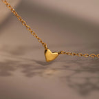 Heart Station Necklace featuring a delicate gold cable chain and a small, simple heart pendant, beautifully displayed against a soft, blurred background.