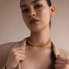 A woman in a beige blazer confidently looks at the camera, her Chunky Link Mesh Necklace making a bold statement and elevating her outfit.