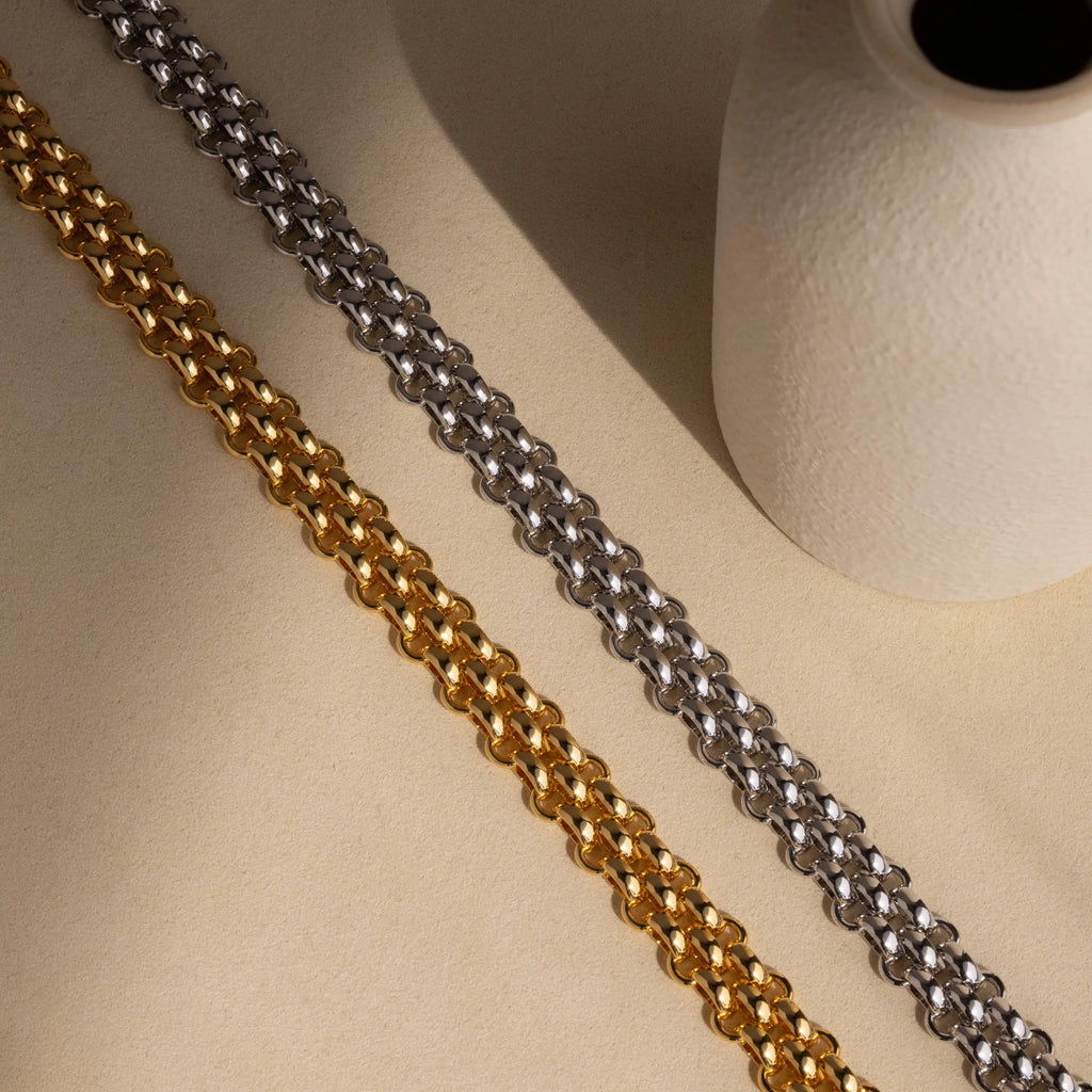 The Chunky Link Mesh Necklace is displayed diagonally next to a textured white ceramic vase on a beige surface—an eye-catching statement piece for bold jewelry styling.
