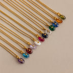 Close up of 12 Gold North Star Birthstone Pendant Necklaces laid out in a row.