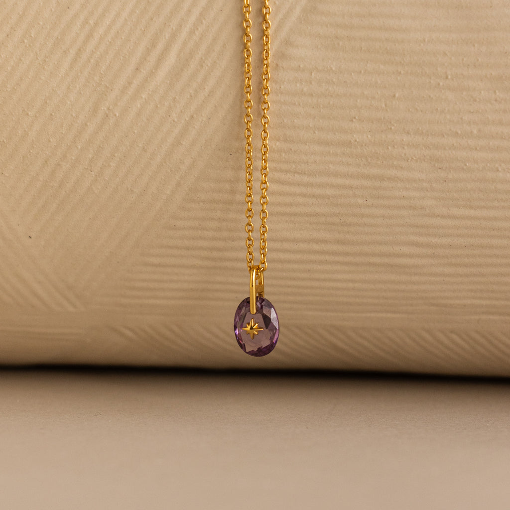 Close up of a Gold North Star Birthstone Necklace with a Purple Amethyst Gemstone.