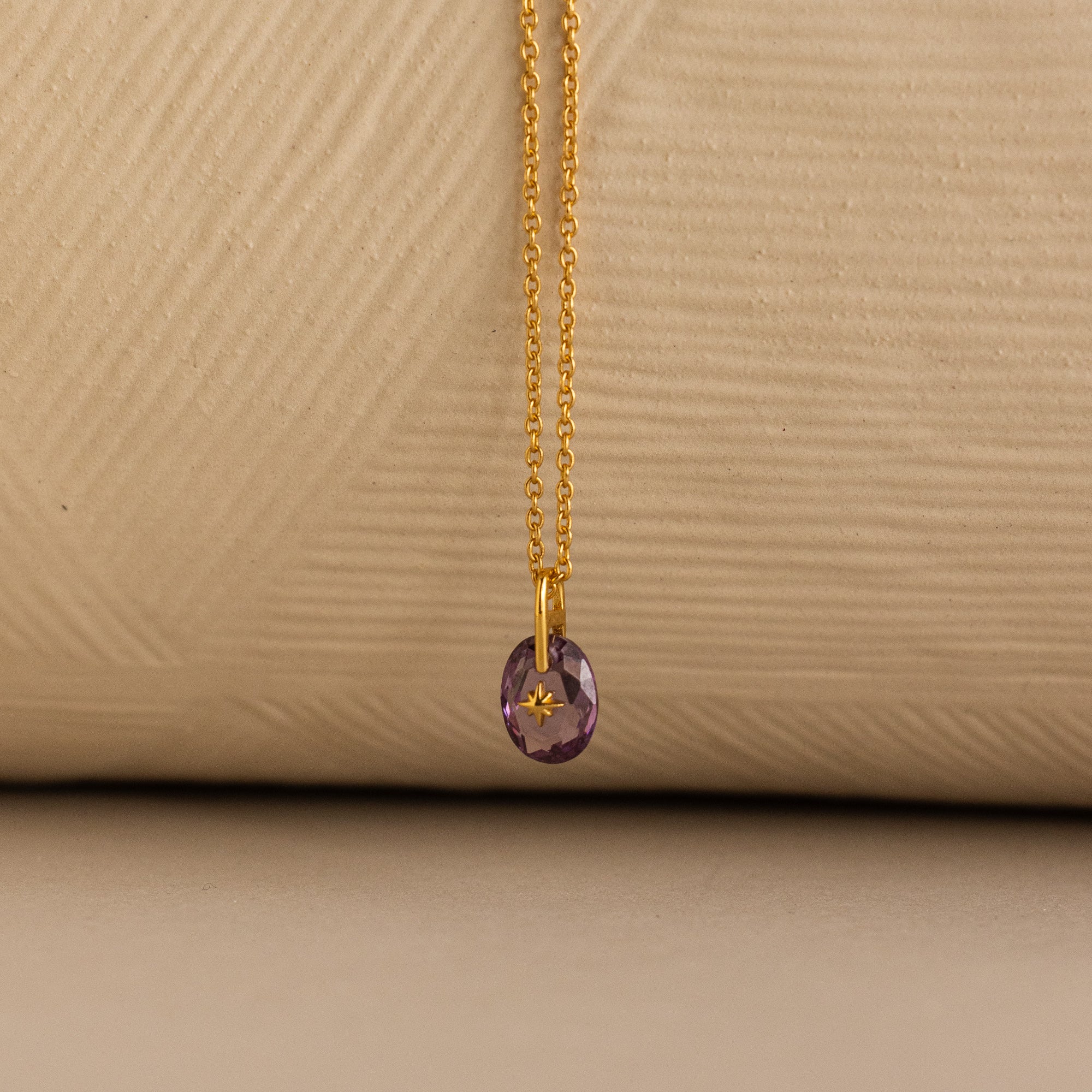 Close up of a Gold North Star Birthstone Necklace with a Purple Amethyst Gemstone.