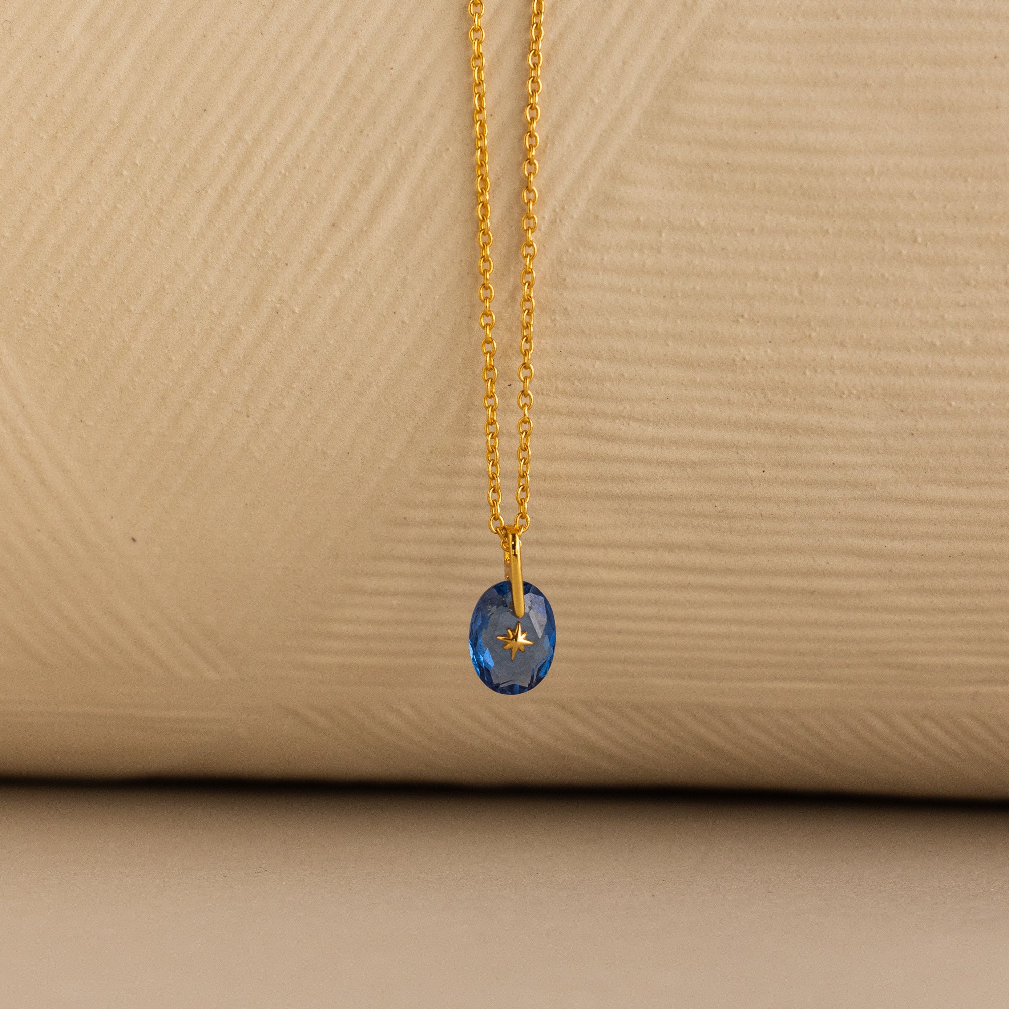 Close up of a Gold North Star Birthstone Necklace with a Blue Aquamarine Gemstone.