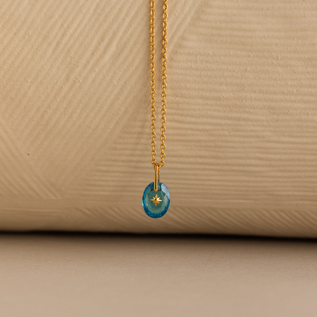 Close up of a Gold North Star Birthstone Necklace with a Blue Turquoise Zircon Gemstone.