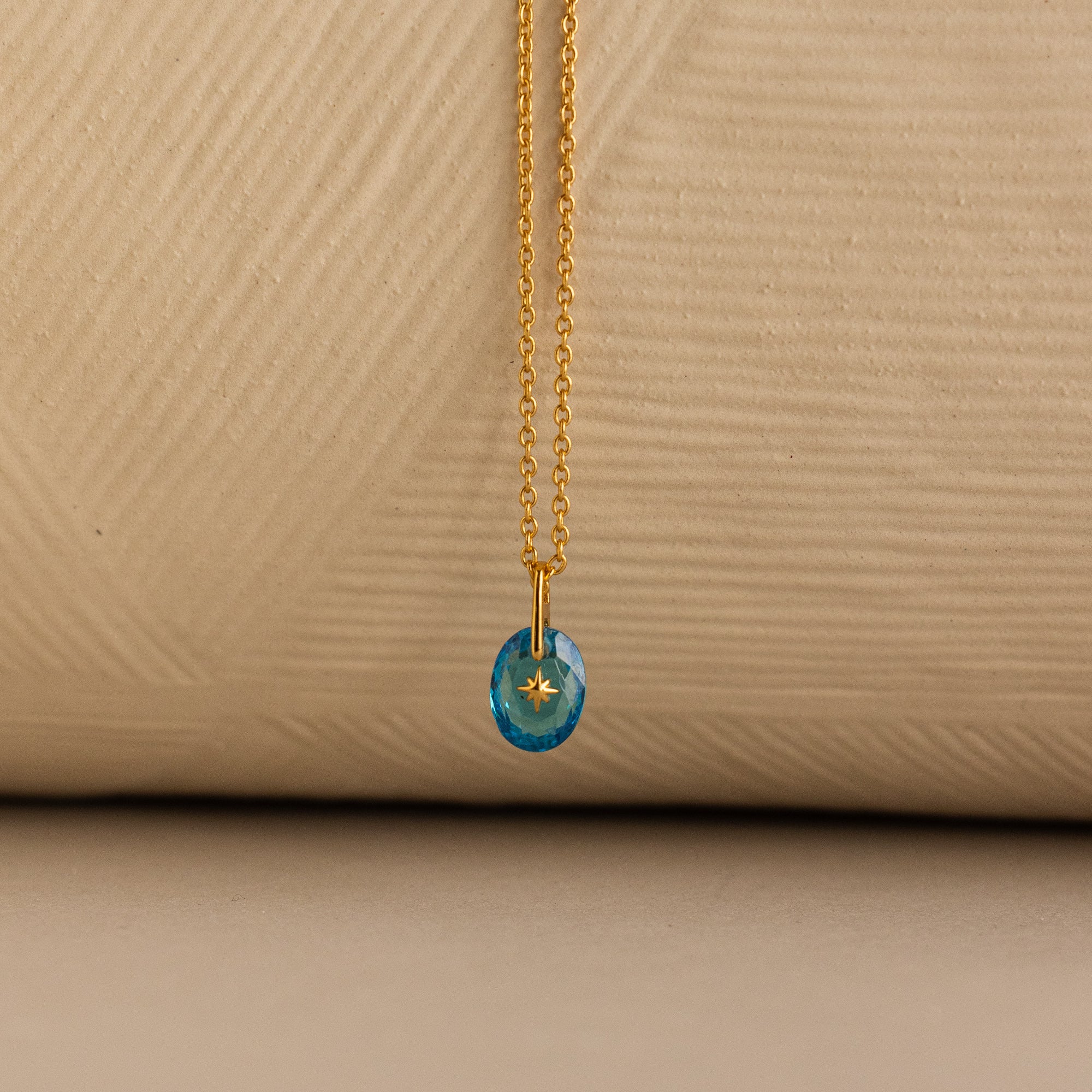 Close up of a Gold North Star Birthstone Necklace with a Blue Turquoise Zircon Gemstone.