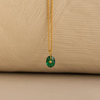 Close up of a Gold North Star Birthstone Necklace with a Green Emerald Gemstone.