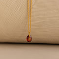 Close up of a Gold North Star Birthstone Necklace with a Red Garnet Gemstone.