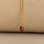 Close up of a Gold North Star Birthstone Necklace with a Red Garnet Gemstone.