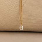 Close up of a Gold North Star Birthstone Necklace with a White Iridescent Opal Gemstone.