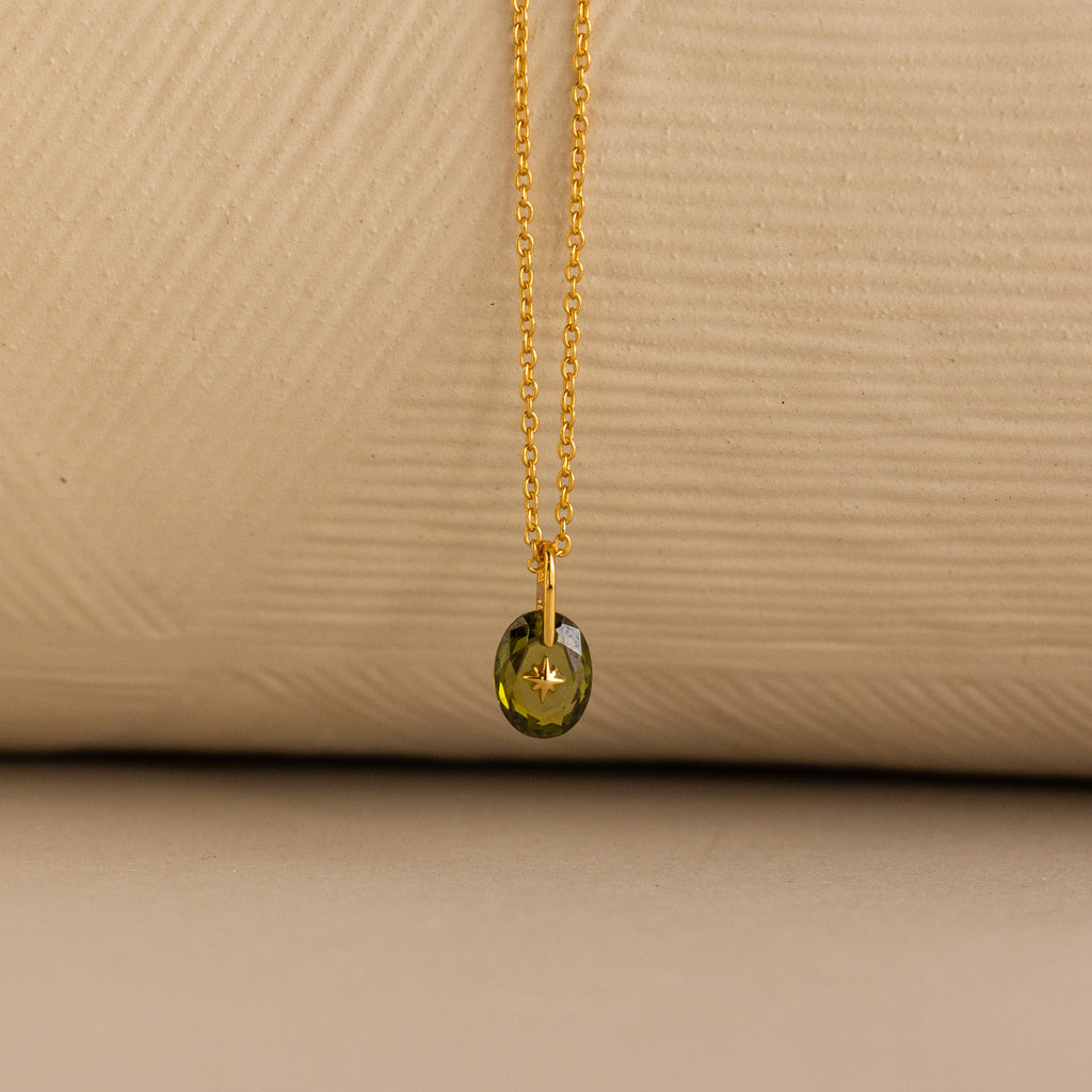Close up of a Gold North Star Birthstone Necklace with a Green Peridot Gemstone.
