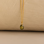 Close up of a Gold North Star Birthstone Necklace with a Green Peridot Gemstone.