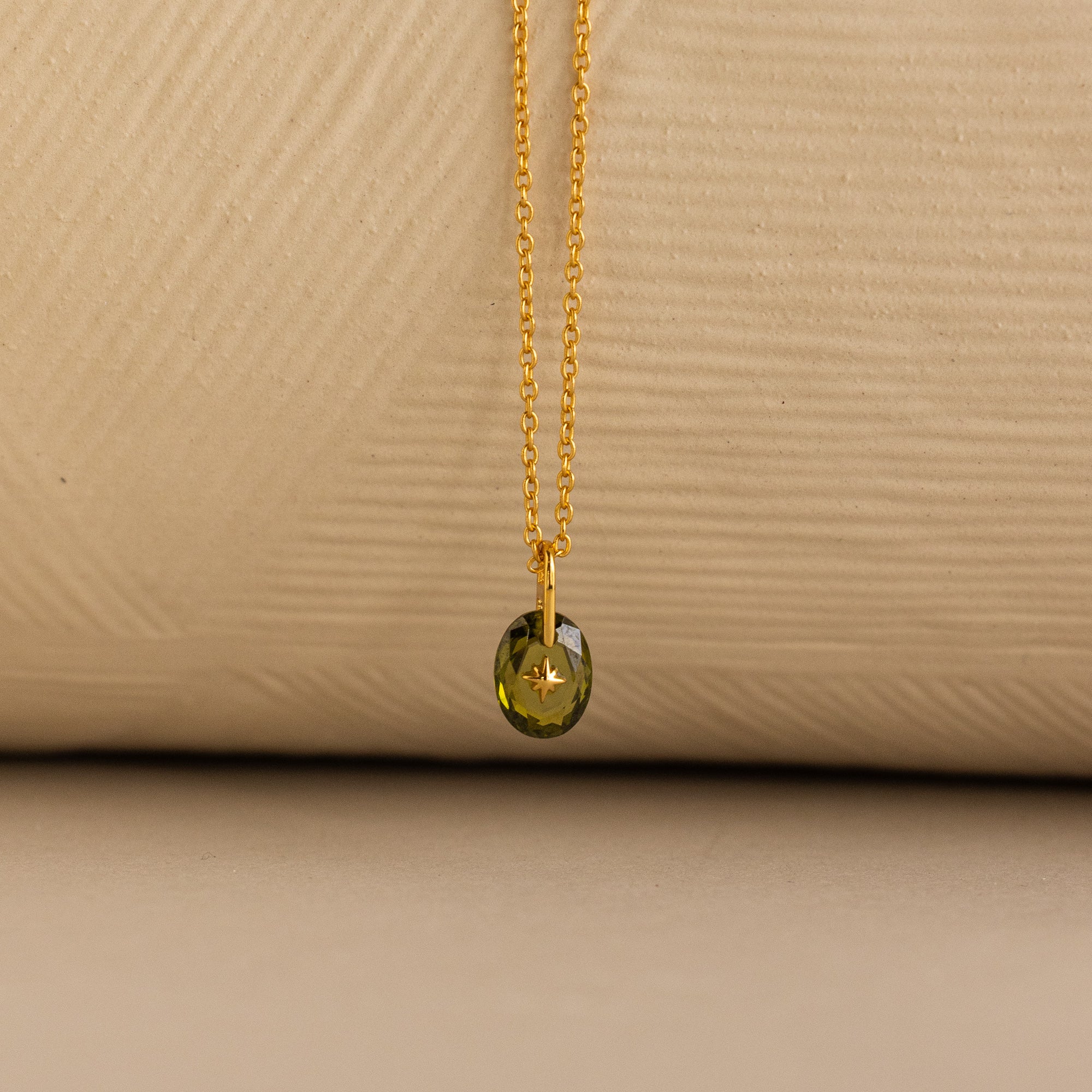 Close up of a Gold North Star Birthstone Necklace with a Green Peridot Gemstone.