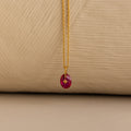 Close up of a Gold North Star Birthstone Necklace with a Pink Ruby Gemstone.