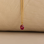 Close up of a Gold North Star Birthstone Necklace with a Pink Ruby Gemstone.