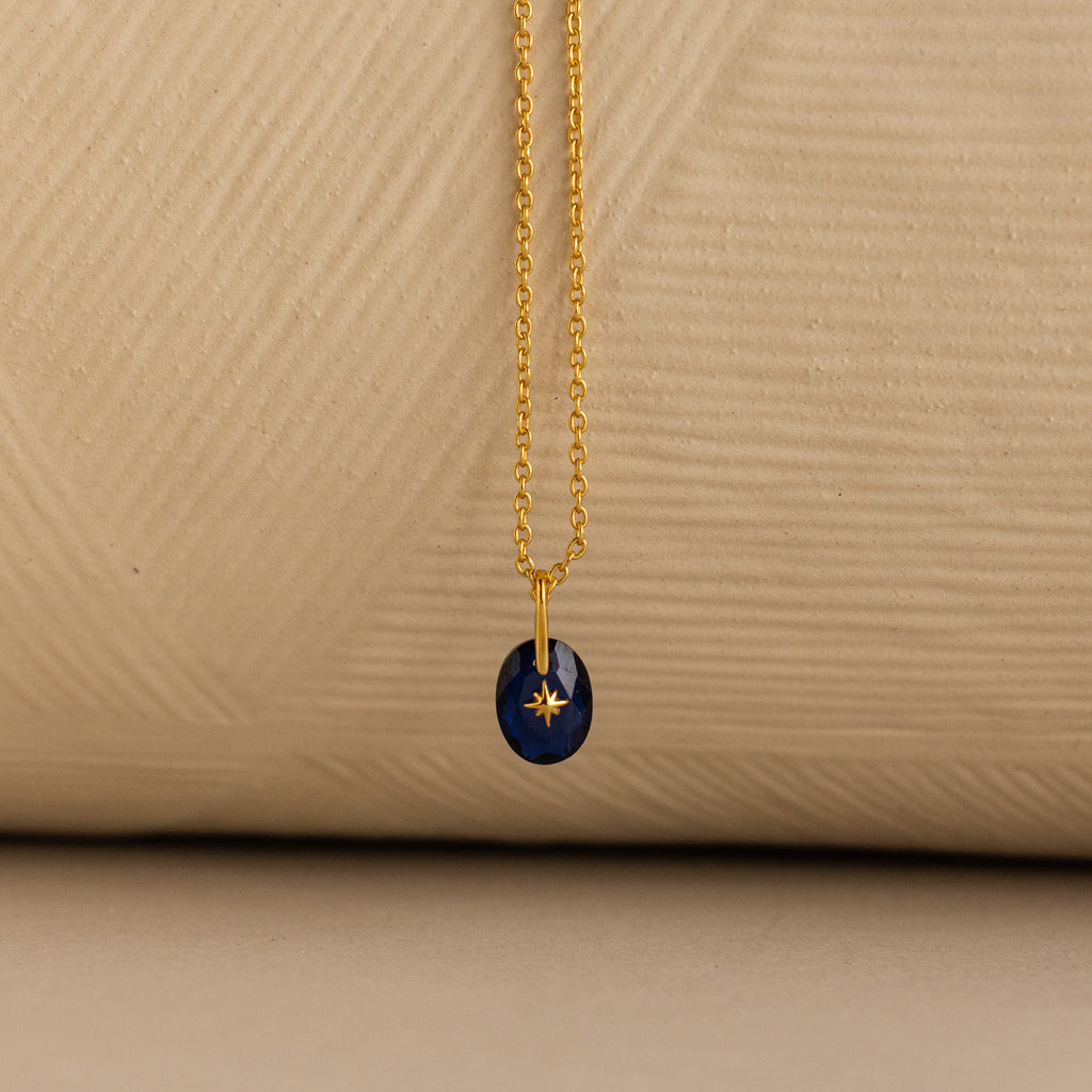Close up of a Gold North Star Birthstone Necklace with a Blue Sapphire Gemstone.