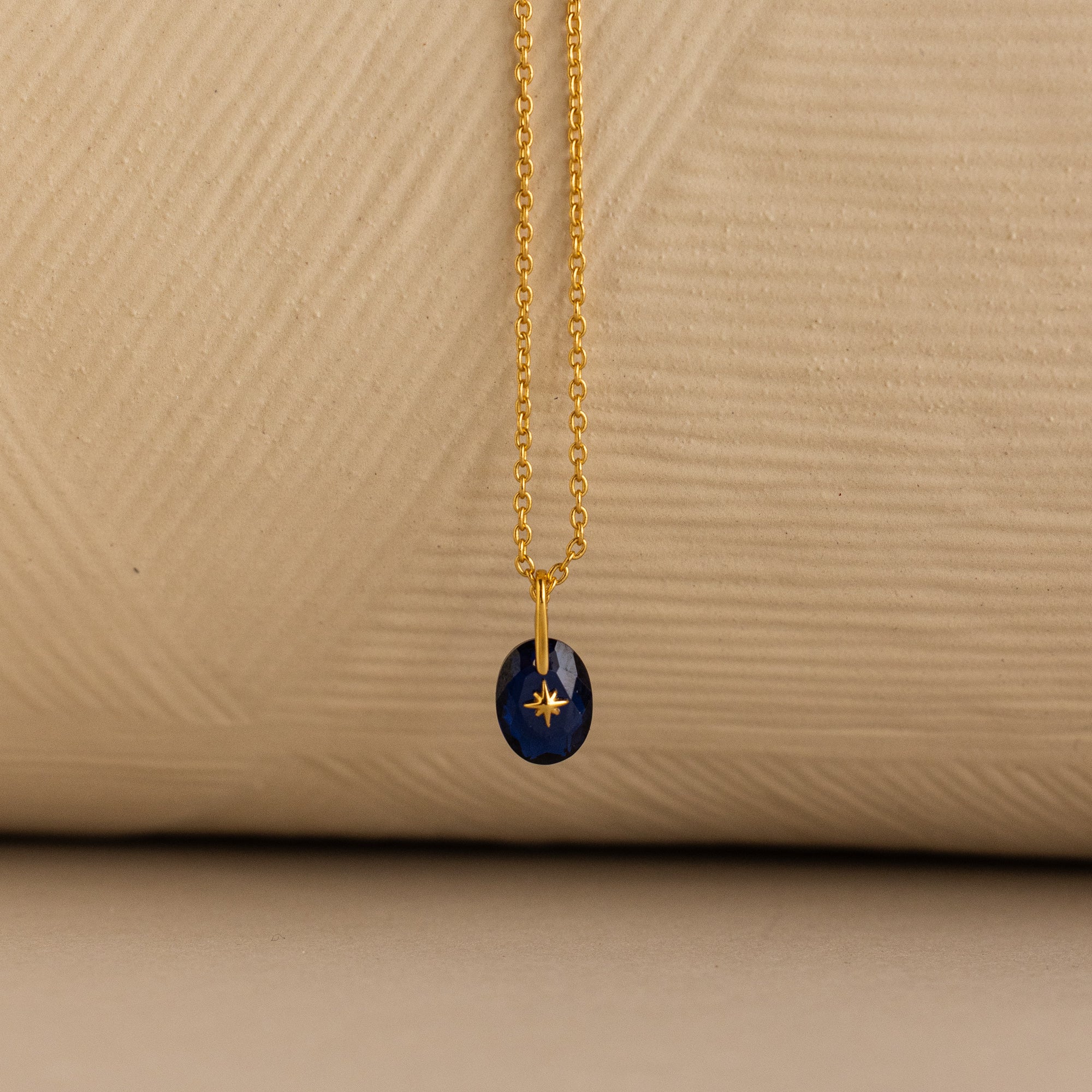 Close up of a Gold North Star Birthstone Necklace with a Blue Sapphire Gemstone.