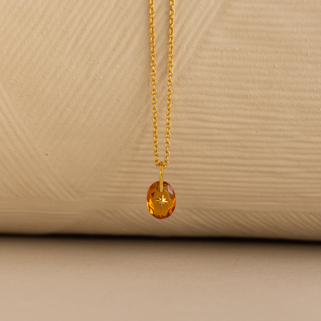 Close up of a Gold North Star Birthstone Necklace with a Yellow Topaz Gemstone.