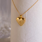 A gold heart-shaped locket with a north star CZ diamond in the center on a delicate cable chain.