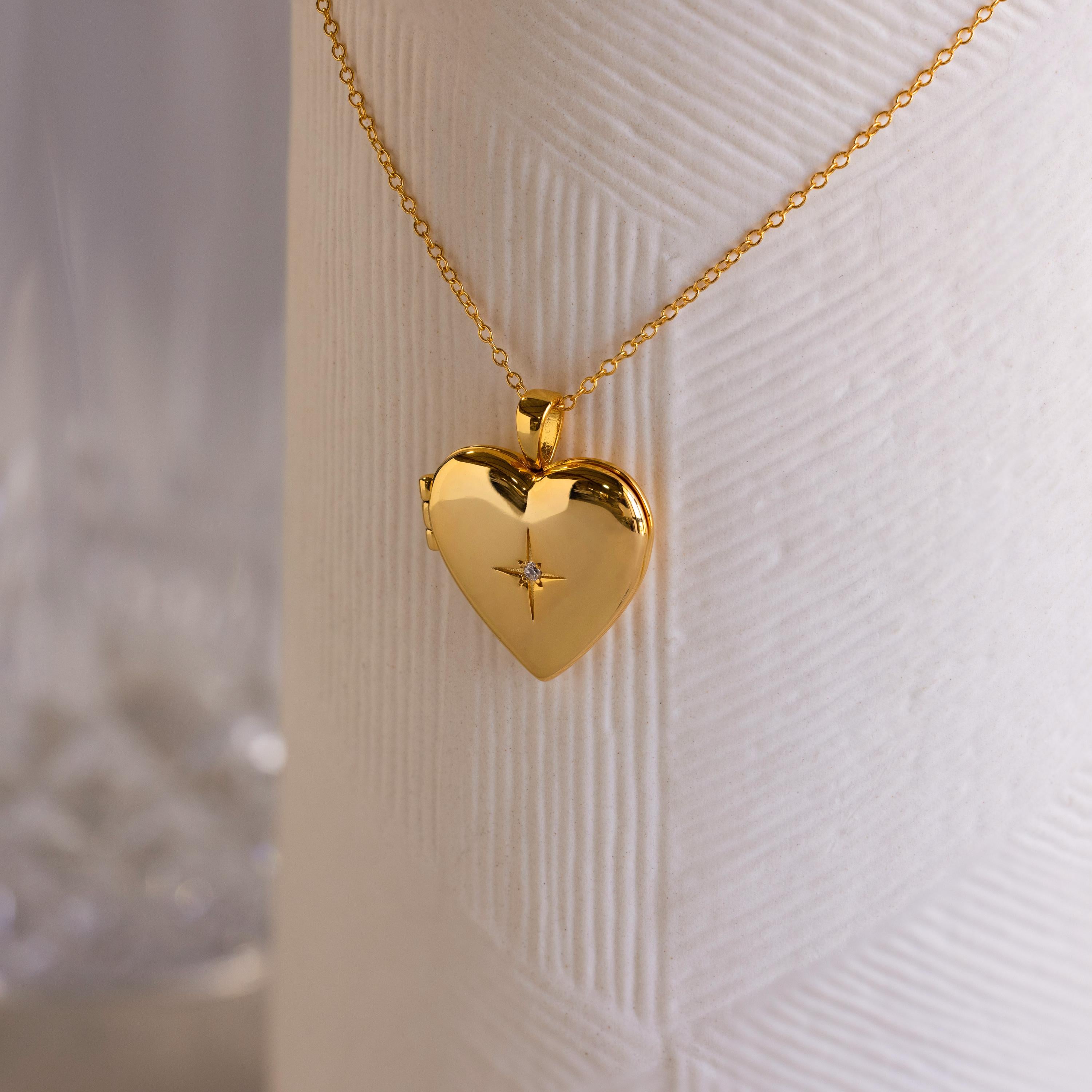 A gold heart-shaped locket with a north star CZ diamond in the center on a delicate cable chain.