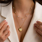 Model wearing a Gold North Star Heart Locket Necklace, layered with a Gold Diamond Flower Drop Necklace.