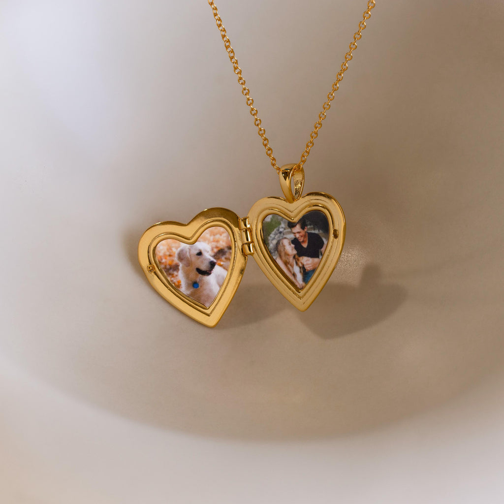 Up close of gold heart-shaped locket pendant necklace opened with 2 personal photos inside.