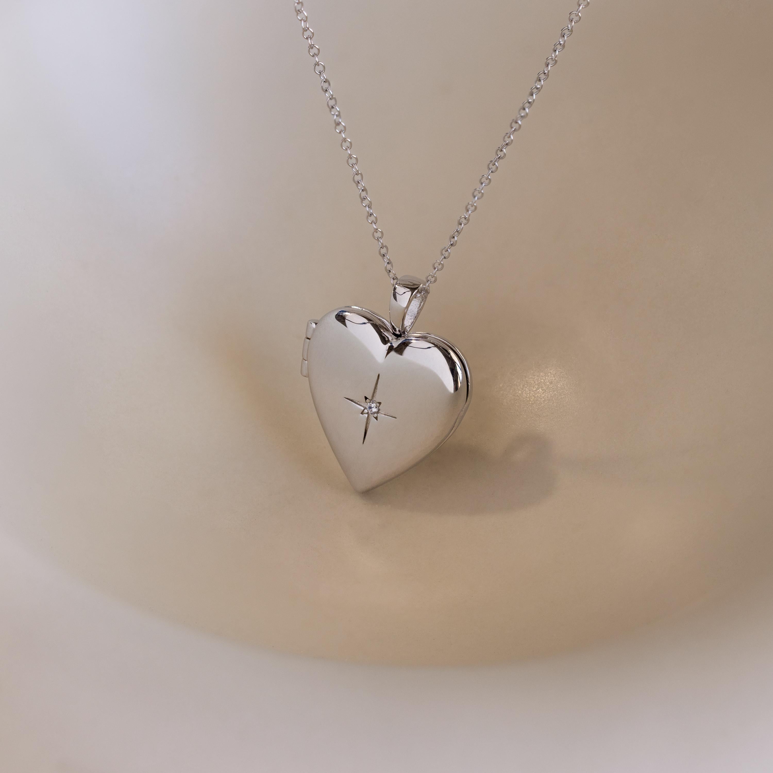 A silver heart-shaped locket with a north star CZ diamond in the center on a delicate cable chain.