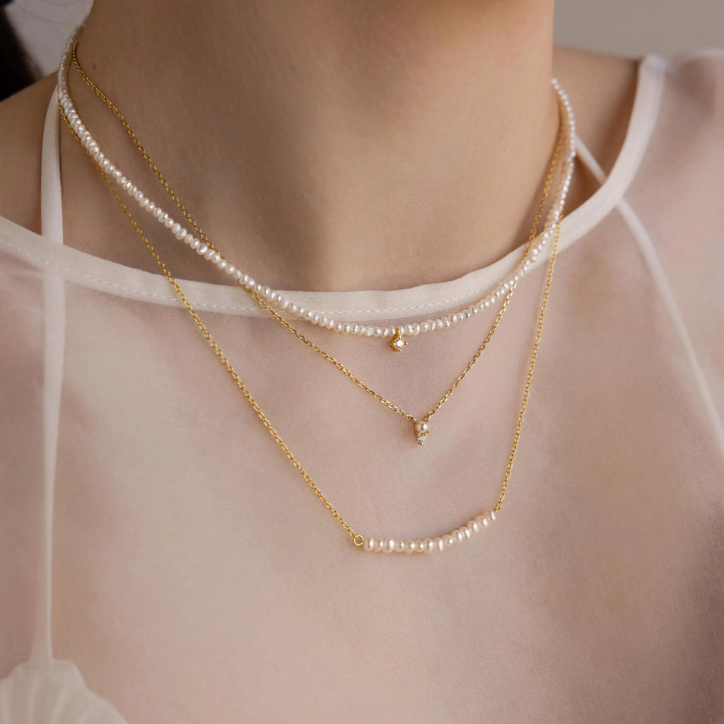 The Pearl Curve Necklace, layered over a sheer white top, makes a stunning bridal jewelry choice.
