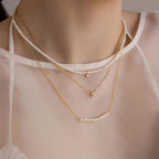The Pearl Curve Necklace, layered over a sheer white top, makes a stunning bridal jewelry choice.
