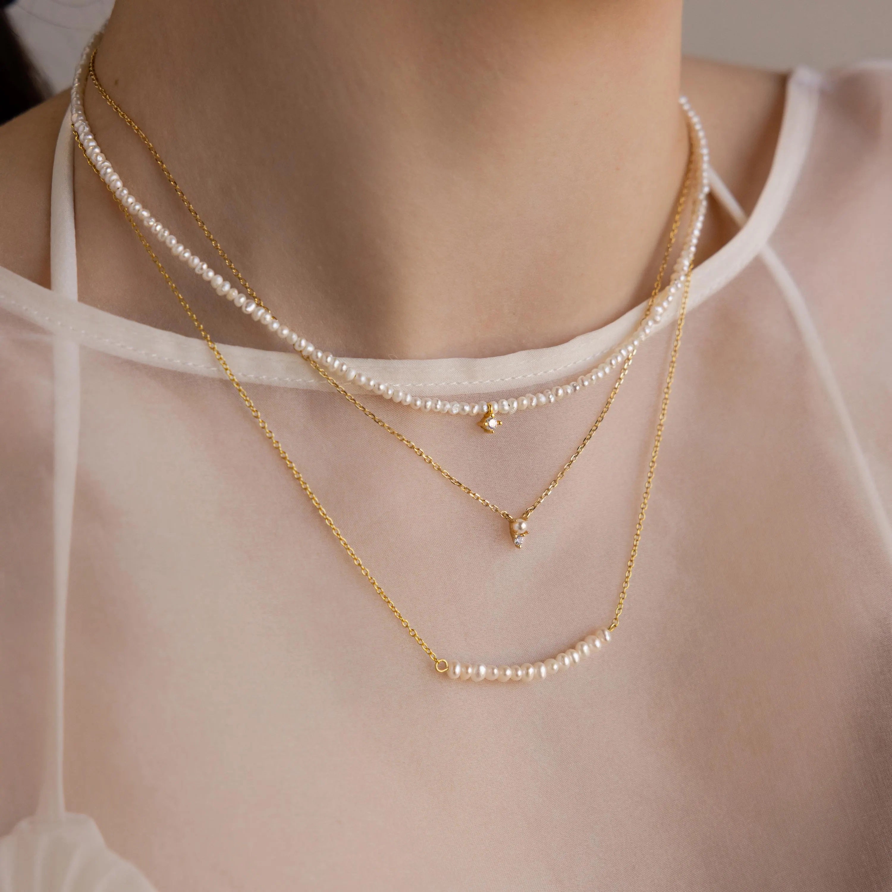 The Pearl Curve Necklace, layered over a sheer white top, makes a stunning bridal jewelry choice.